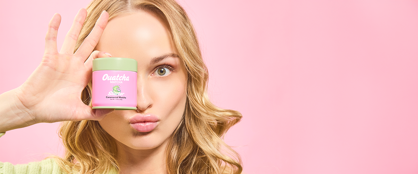 Woman holding a pink Ouatcha Matcha tin with a green lid against a pink background