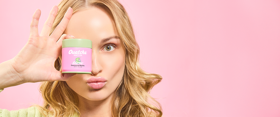 Woman holding a pink Ouatcha Matcha tin with a green lid against a pink background
